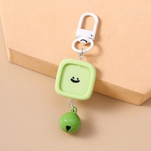 Détail d'un porte-clés vert avec pendentif souriant en résine et petite clochette