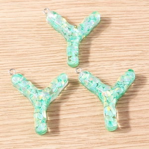Detailed macro view of mint green resin letter Y pendants with iridescent glitter inlay