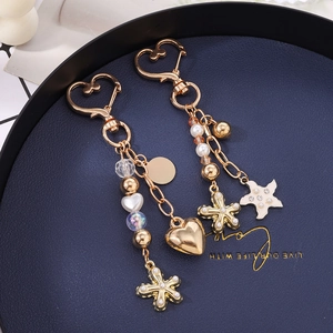 Pendentif de sac perlé avec cœur et étoile de mer et fermoir mousqueton doré chic