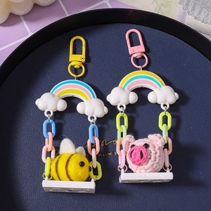 Handmade crochet pig and bee swing keychain with rainbow charms on blue tray
