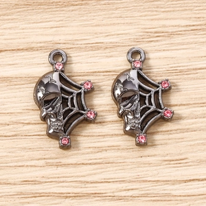 Macro shot of gothic spider web and skull charms with pink rhinestones for DIY jewelry