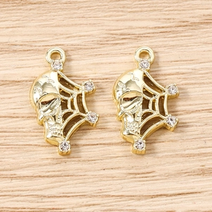 Macro detail of gold skull and spider web charms with sparkling white rhinestones