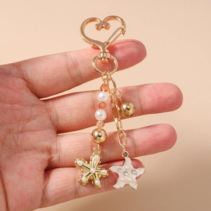 Détail d'un porte-clés étoile de mer doré avec des perles et un fermoir en cœur