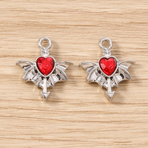 Detailed close-up of gothic silver bat wing charms with red heart jewels for DIY jewelry