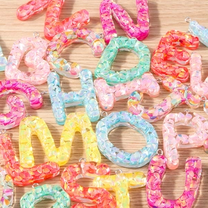 Macro shot of colorful resin alphabet charms with glitter and silver metal rings