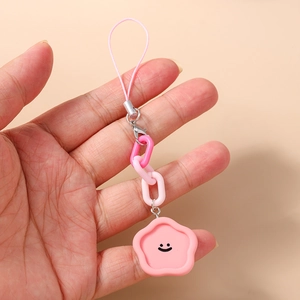 Détail d'un charme fleur rose avec visage souriant sur chaîne en plastique et fermoir