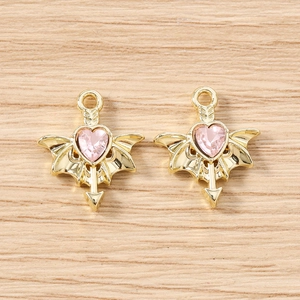 Detail of gothic wing heart charms with pink gemstone and gold finish for DIY crafts