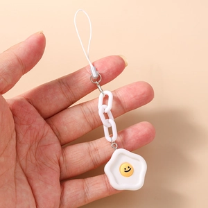 Détail de la dragonne de téléphone œuf au plat avec un visage souriant jaune