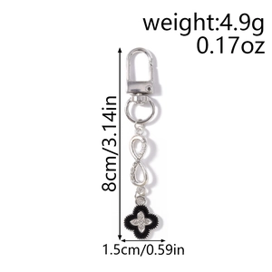Detail of silver infinity symbol keychain with rhinestones and black clover charm