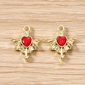 Macro detail of red heart wing charms with gold alloy base and Cupid arrow for DIY jewelry