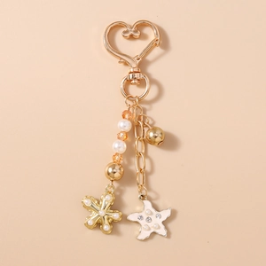 Détail du porte-clés cœur perlé avec étoile de mer dorée et breloques de fleurs perlées