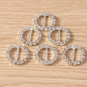 Close-up of six circular silver rhinestone buckles on a natural wood background