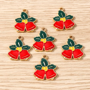 Vue détaillée de breloques clochettes de Noël en émail coloré avec feuilles de houx
