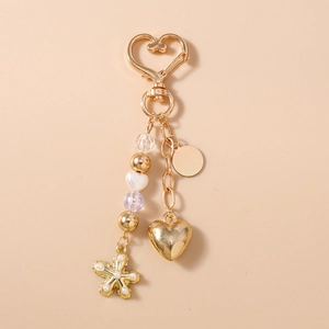 Détail d'un porte-clés doré en forme de cœur avec perles et pendentif étoile de mer