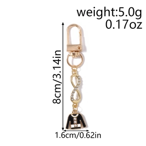 Detail view of gold-tone infinity keychain with rhinestones and black enamel jacket charm