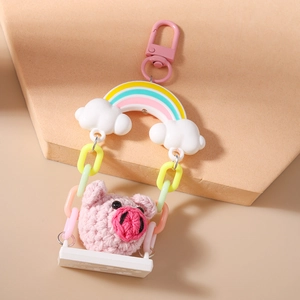 Detailed close-up of a crochet pig keychain on a rainbow swing with colorful plastic chains