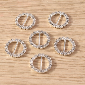 Detail of six silver round rhinestone slide buckles for scarves on a wood background