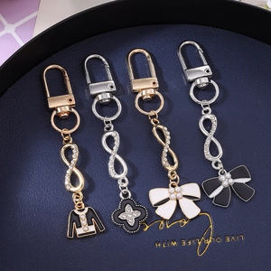 Fashion metal keychain with rhinestone flower, bow, and mini jacket charms on blue base