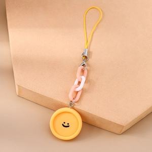 Détail d'un bijou de téléphone sourire jaune avec chaîne rose et blanche sur socle
