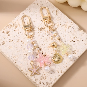 Beaded pearl keychain with starfish and shell charms on a decorative stone base
