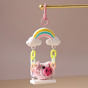 Close-up of handmade crochet pig on rainbow swing charm with pink lobster clasp