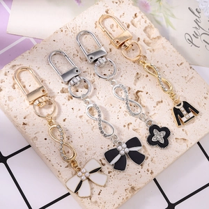 Fashionable rhinestone keychain set featuring butterfly bow and clover charms on stone
