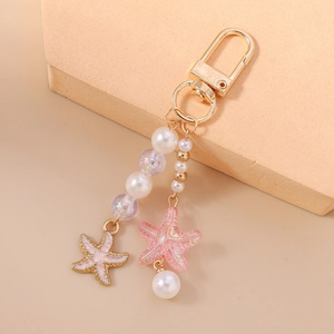 Detail of beaded keychain with pink starfish charms and elegant white pearls on golden ring