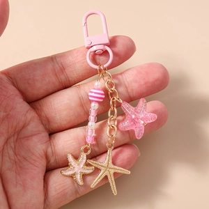 Détail d'un porte-clés étoile de mer rose avec perles et breloques en métal à la main