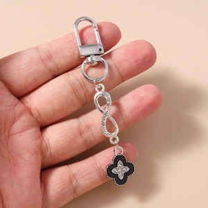 Close-up of silver D-clasp keychain featuring a black clover pendant with rhinestone inlay