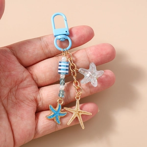 Détail des pendentifs étoile de mer et des perles rayées bleues sur un porte-clés marin