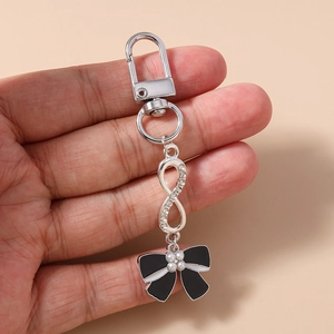 Detailed view of silver infinity keychain with rhinestones and black white bow