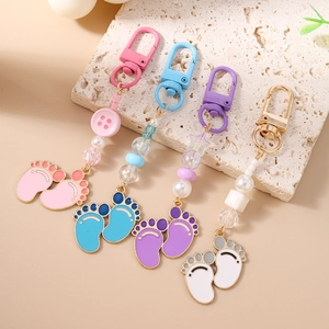 Colorful baby footprint keychains with star beads and pearls on a natural stone background