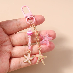 Détail des breloques étoile de mer roses avec perles rayées sur le porte-clés étoile de mer