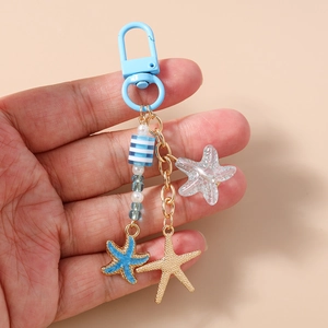 Détail macro du porte-clés étoile de mer nautique avec perles bleues et émail doré