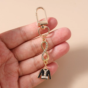 Detail of gold infinity keychain with rhinestone accents and monochrome dress charm
