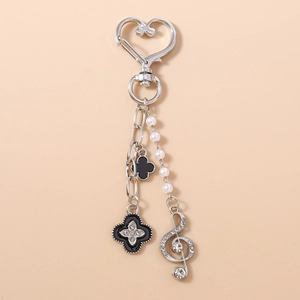 Détail de porte-clés à fermoir cœur argenté avec chaîne perles et trèfle noir