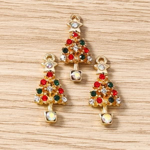 Détail de trois breloques sapin de Noël avec strass colorés sur une base dorée