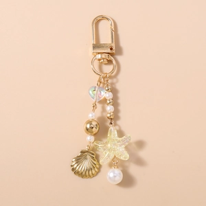 Detail of a gold ocean-themed keychain with pearl, seashell, and starfish charms