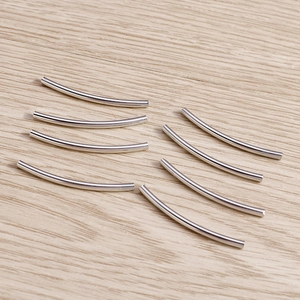 Perles tubes courbés en argent poli pour bijoux DIY sur fond de bois