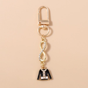 Detail of gold keychain featuring a rhinestone infinity symbol and black enamel sweater charm