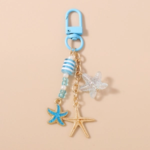 Détail des pendentifs étoile de mer avec perles à rayures bleues et chaîne dorée
