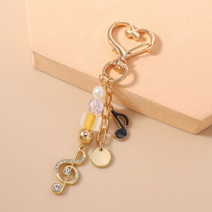 Détail d'un porte-clés musical avec perles, clé de sol et note noire sur un fermoir en cœur