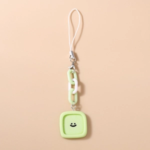 Détail d'une dragonne de téléphone vert clair avec un pendentif carré à visage souriant