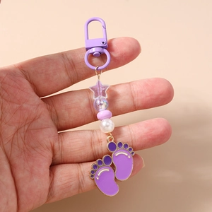 Detailed view of a purple star bead and enamel foot charms on a beaded keychain