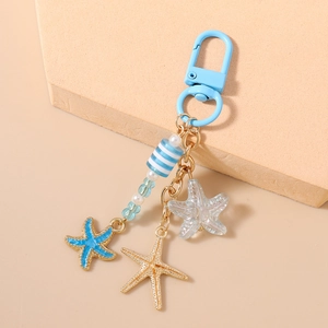 Détail d'un porte-clés nautique avec fermoir bleu ciel et breloques en forme d'étoile de mer