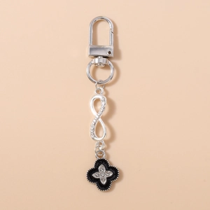 Detail of silver infinity charm with rhinestones and black clover pendant on keychain