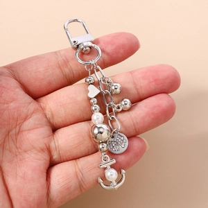 Détail d'un porte-clés argenté avec perles, ancre et pendentif nœud en strass brillant
