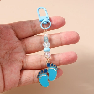 Detail of blue baby footprint charm with beads and lobster clasp held in hand