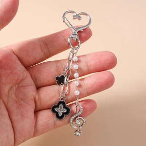 Détail du porte-clés en perles avec breloques trèfle noir et pendentif clé de sol