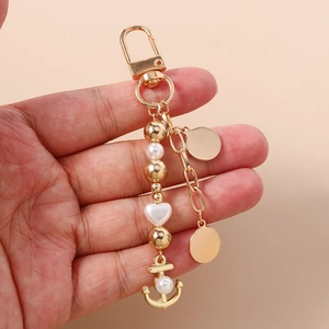 Vue détaillée d'un porte-clés ancre doré avec perles blanches et pendentifs ronds
